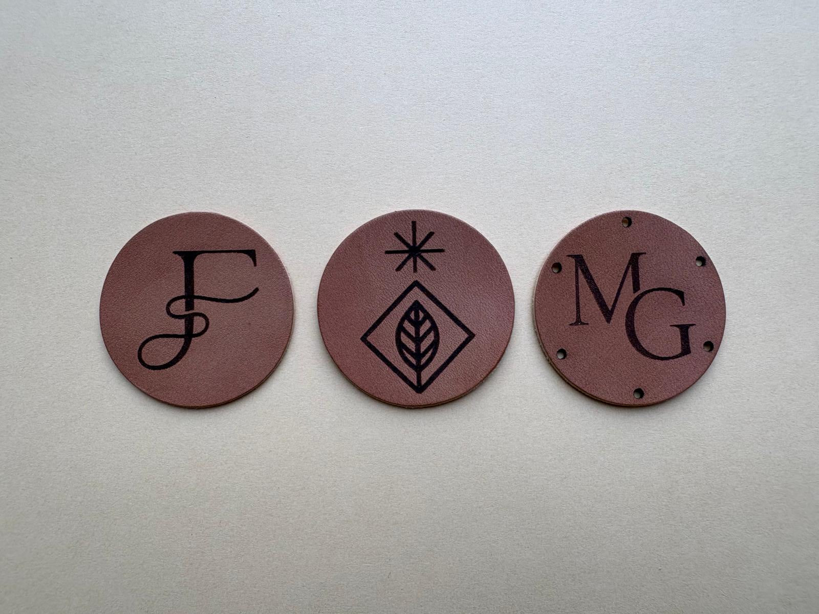 Drie middelgrote ronde leren labels met verschillende ontwerpen